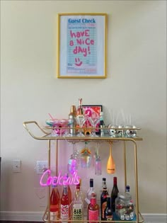 a bar cart filled with liquor bottles and glasses next to a framed poster on the wall