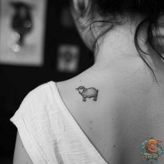 a small sheep tattoo on the back of a woman's neck