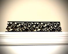 an ornate metal shelf on top of a white mantle