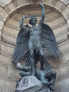 an angel statue on top of a rock in front of a building