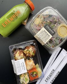 two plastic containers filled with food sitting on top of a table next to a green bottle