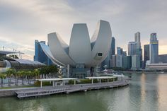 a large flower sculpture sitting on top of a river next to a tall city skyline