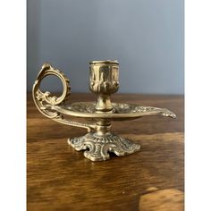 an antique brass candle holder on a wooden table