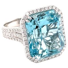 This stunning cocktail ring showcases a beautiful 16.79 Carat Emerald Cut Aquamarine with a Diamond Halo on a Triple Diamond Shank. This ring is set in 18k White Gold. Total Diamond Weight = 1.12 Carats. Ring Size is 6 1/2. Luxury Aquamarine Diamond Ring With Emerald Cut, Formal Emerald-cut Aquamarine Ring, Luxury Blue Aquamarine Diamond Ring, Blue Aquamarine Emerald-cut Diamond Ring, Luxury Aquamarine Emerald-cut Rings, Aquamarine Cocktail Ring, Bling Ideas, Diamond Cocktail Ring, Stylish Rings