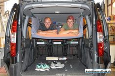 two men sitting in the back of a van