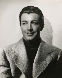 an old black and white photo of a man in a coat smiling at the camera