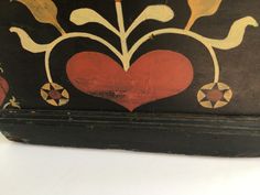 an old wooden box with painted designs on the inside and sides, including a heart