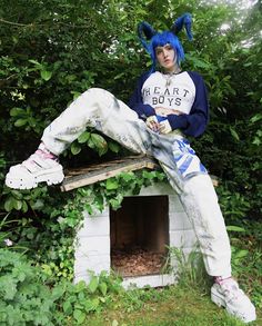 a woman with blue hair sitting on top of a dog house