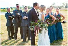 a bride and groom kissing in front of their wedding party