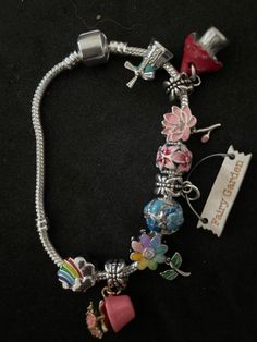 a bracelet with charms on it sitting on a black surface next to a tag that says happy birthday