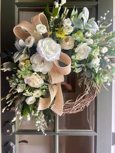 a wreath with white flowers and greenery hangs on the front door