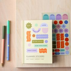 two planner stickers next to each other on a table with a pen and notebook