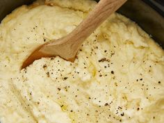 a wooden spoon stirring mashed potatoes in a pot