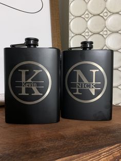 two black flasks sitting on top of a wooden table