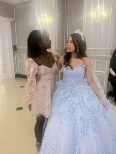 two women in dresses standing next to each other and one is wearing a tiara