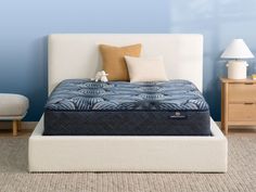 a bed with blue and white mattresses in a room next to two nightstands