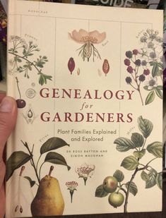 a person holding up a book with pictures of plants and flowers on it's cover