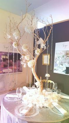 the table is decorated with white flowers and branches, which are hanging from chains on it