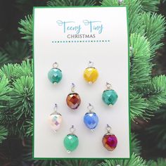 six christmas ornaments hanging from a tree with a card in the foreground that says merry tiny