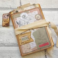 an altered book is tied up against a white brick wall with a tag attached to it