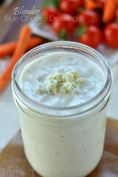 a glass jar filled with food sitting on top of a cutting board next to carrots