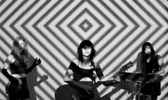 three women in black and white are playing guitars