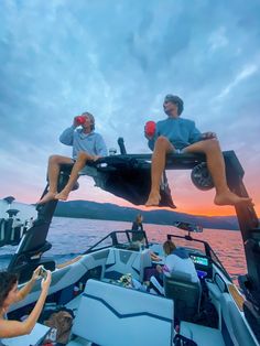 two men sitting on the back of a boat with their feet up in the air