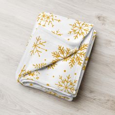 a yellow and white snowflake print blanket folded on a wooden table with wood flooring