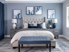 a bedroom with blue and white decor on the walls, gray bedding, and two framed pictures