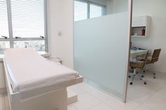 an empty hospital room with a bed in the middle and a desk on the other side