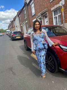 a woman standing next to a red car in front of a brick building on the street