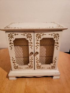 a white cabinet with two glass doors on top of a wooden table next to a wall