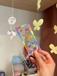 a person holding up a cell phone case with butterflies on it and hanging from the ceiling