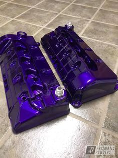 two purple engine covers sitting on top of a tile floor