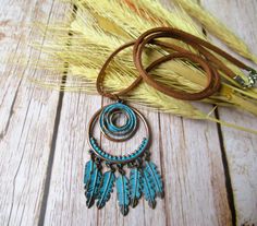 a necklace with feathers hanging from it on a wooden table next to some wheat stalks