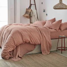 a bed with red and white striped linens in a room next to a window