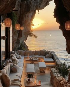 an outdoor living area with couches and tables overlooking the ocean at sunset or sunrise