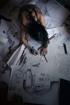 a woman laying on top of papers with scissors in her hand and writing on the paper