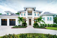 a large white house with two garages and palm trees