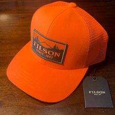 C.C. Filson Logger Mesh Cap, Trucker Hat, Filson Hat, Blaze Orange Orange Curved Brim Trucker Hat For Outdoor, Orange Baseball Cap For Outdoor, Orange Snapback Hat For Outdoor, Outdoor Orange Snapback Hat, Orange Curved Brim Snapback Hat For Outdoor, Orange Snapback Hat With Curved Brim For Outdoor, Outdoor Orange Snapback Hat With Curved Brim, Orange Curved Brim Hat For Outdoor, Olive Tan