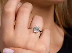 a close up of a person wearing a ring with a baguette on it