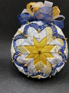 an ornament is decorated with blue and yellow fabric, gold accents and a star