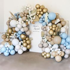 an arch made out of balloons with flowers and leaves on the front is decorated in gold, white and blue