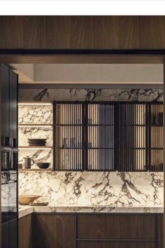 an open kitchen with marble counter tops and wooden cabinetry, along with black cupboards