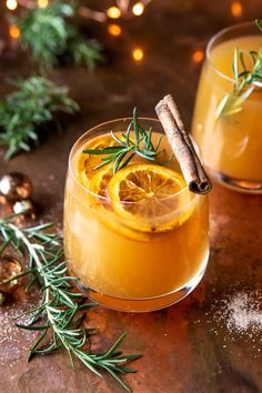 two glasses filled with orange and rosemary drink