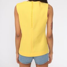 "Vintage 70s tank top in yellow. Sleeveless with a round neckline. Rear zipper. Note: The colour is blowing out a bit, it's not as bright in person. Every garment we sell is authentic vintage and one-of-a-kind! You will receive the exact item photographed. Condition: Very good vintage. Best fits women's: Small Material: Polyester MEASUREMENTS Taken from seam to seam while the garment is lying flat. Double the armpit, waist, and hips For reference, model is 5'10\" and measures 32-23-34. Length fr Retro Yellow Sleeveless Tank Top, Yellow Retro Sleeveless Tank Top, Retro Yellow Tank Top For Spring, Retro Fitted Sleeveless Tops, Retro Sleeveless Vest Top, Fitted Sleeveless Retro Tops, Retro Tank Tops For Spring, Retro Tank Vest Top, Retro Tank Top Vest