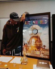 a man standing next to a poster on a table