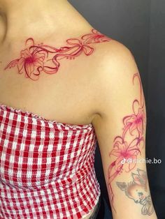 a woman's arm with flowers on it and a checkered shirt underneath her