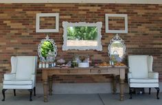 two chairs and a table with food on it in front of a brick walled wall