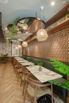 the interior of a restaurant with wooden tables and green booths, hanging plants on the wall